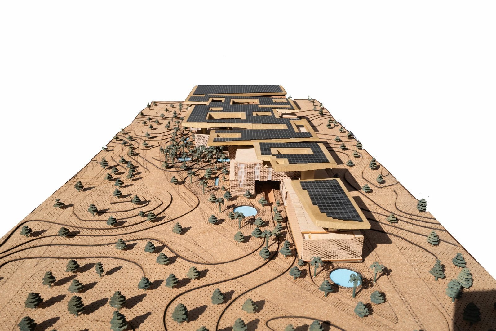 Photograph of the physical scale model of the complex on a contoured landscape base, with photovoltaic panels on the roofs.