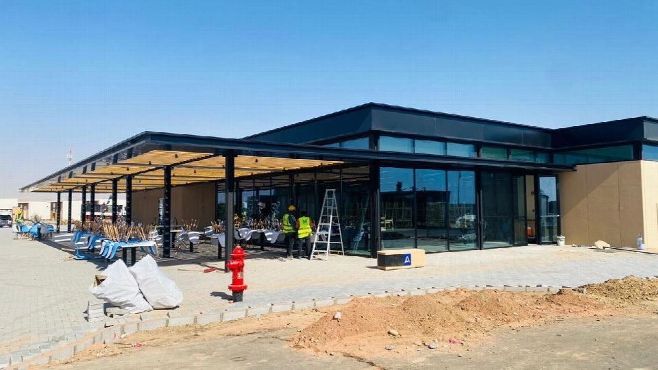 The pavilion building on site during final finishing works, with the terrace furniture being installed.