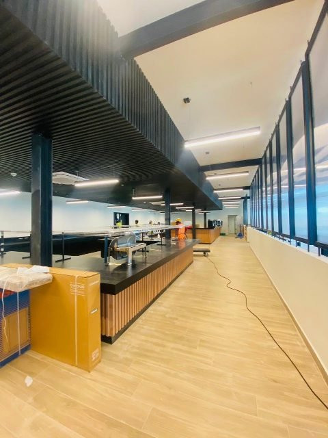 Servery area inside the pavilion during final fit-out, with the buffet counters under the slatted ceiling.